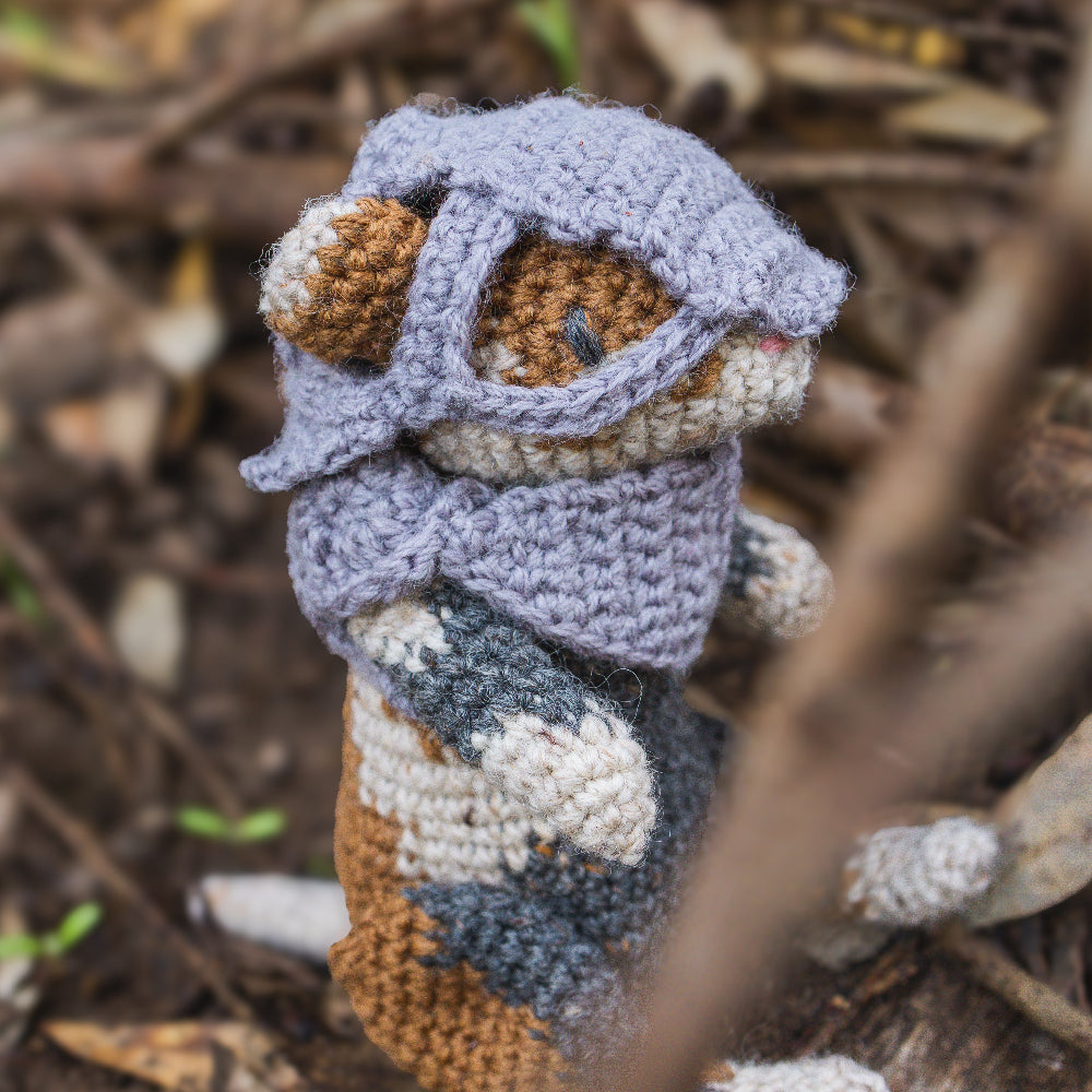 Amigurumi crochet medieval fantasy hamster with helmet sitting in nature